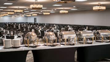 Une salle de banquet avec de nombreuses tables dressées pour le repas, équipée de chariots de buffet en argent et proposant une grande variété de plats.