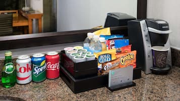 Un dispensador de bebidas con diversas opciones, una máquina de café y un cartel que indica una suite premium.