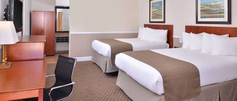 A hotel room with two beds, a desk, a chair, and a TV.