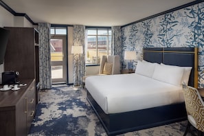A hotel room with a large bed, a desk with a coffee maker, a chair, and a view of the city through the window. - The William Fell Baltimore, Tapestry Collection by Hilton (Baltimore)