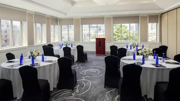 A conference room with round tables, black chairs, and floral centerpieces.