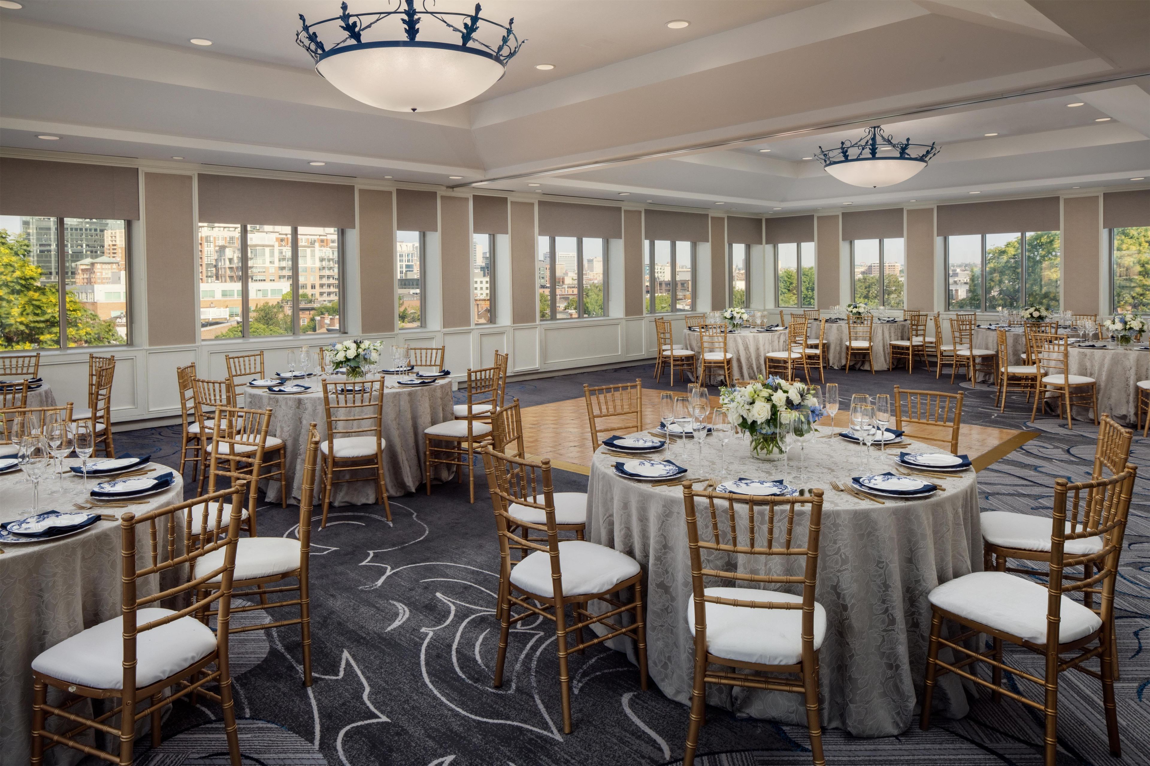 A conference room with round tables, chairs, and chandeliers.