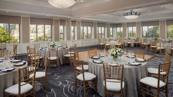 A conference room with round tables, chairs, and chandeliers.