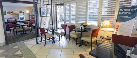 A hotel lobby with a seating area, a vending machine, and a sign about rewards.