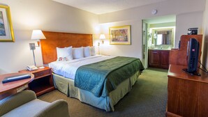 A hotel room with a bed, bedside tables, a desk, a chair, a television, and a bathroom visible through an open door. - Quality Inn Savannah Historic District (Savannah)