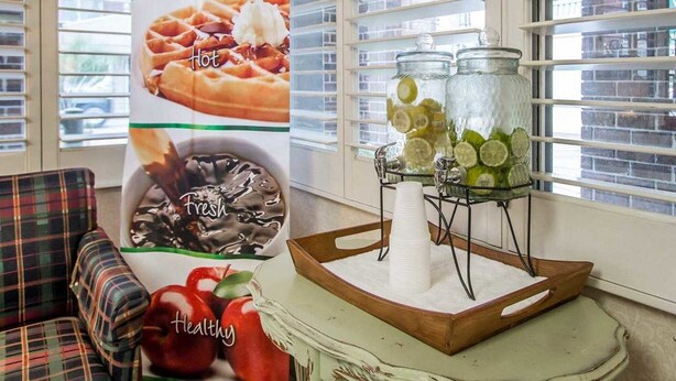 A breakfast setup with a poster advertising a breakfast event, a tray with jars of sliced lemons and limes, and a bowl of fresh strawberries. - Quality Inn Savannah Historic District (Savannah)
