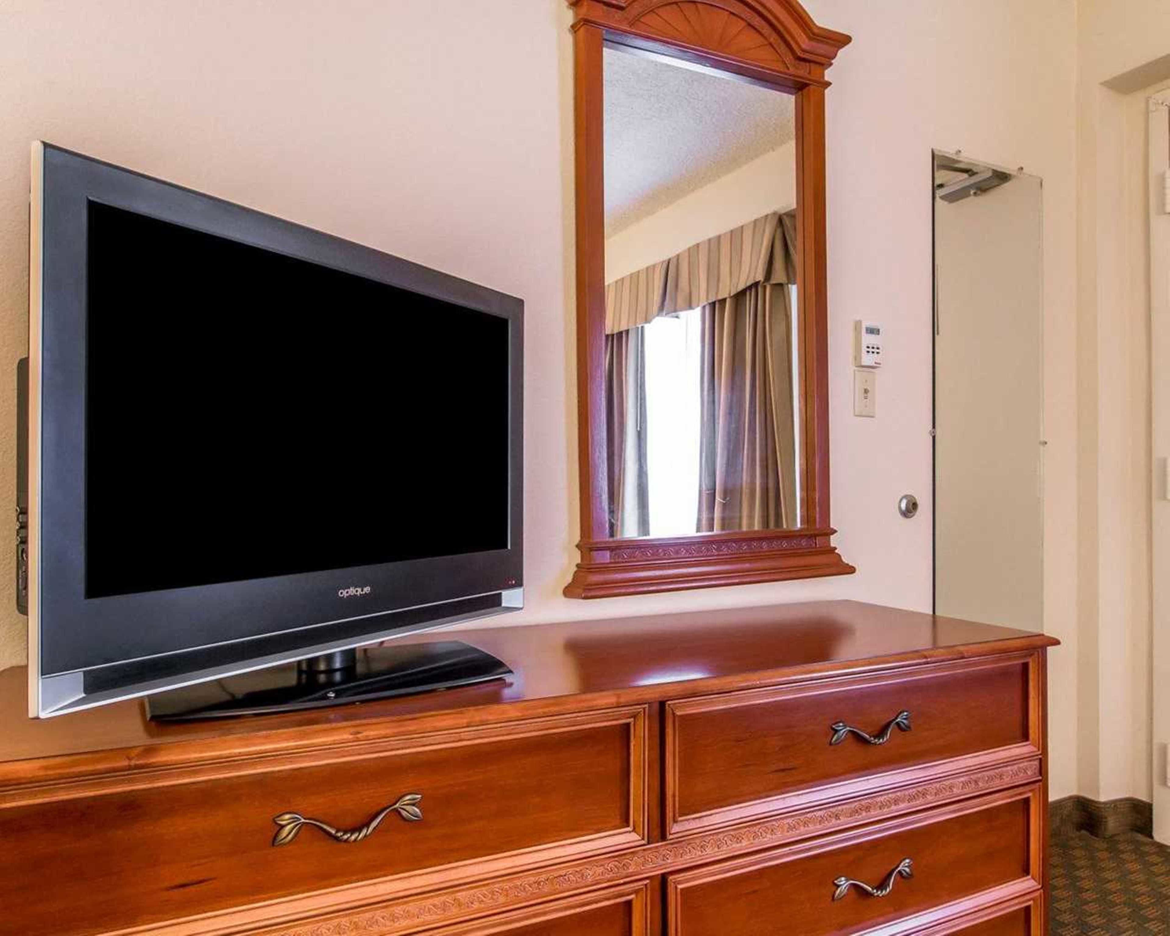 Een televisie op een houten dressoir met lades en een spiegel erboven.