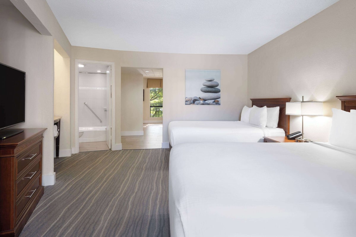Een hotelkamer met een groot bed, een televisie, een bureau en een schilderij van stenen.