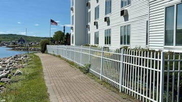 Una passeggiata lungomare con un recinto bianco, una bandiera e un edificio con diverse finestre.