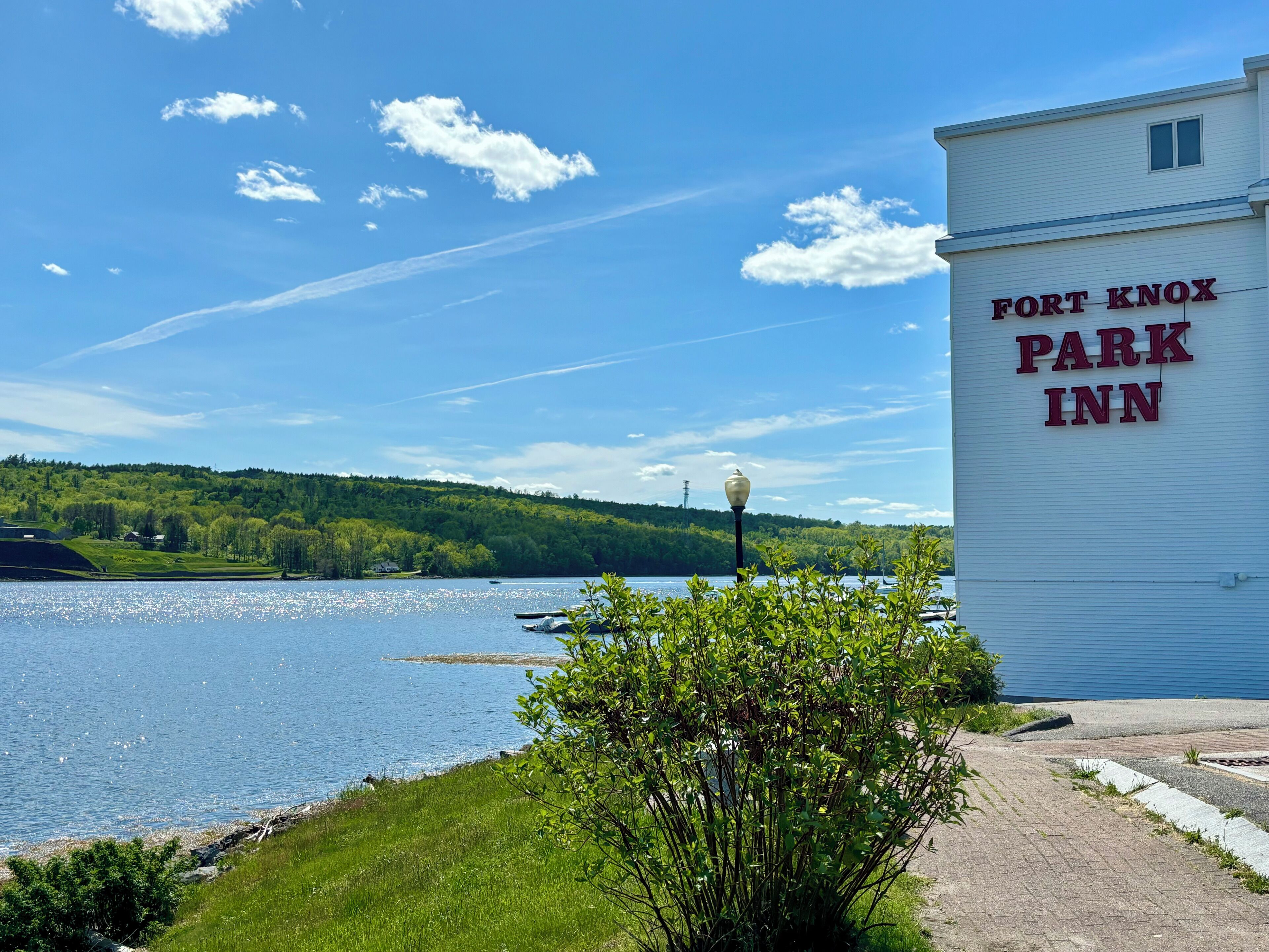 A building labeled "Fort Knox Park Inn" with a view of a lake and forested hills in the background.