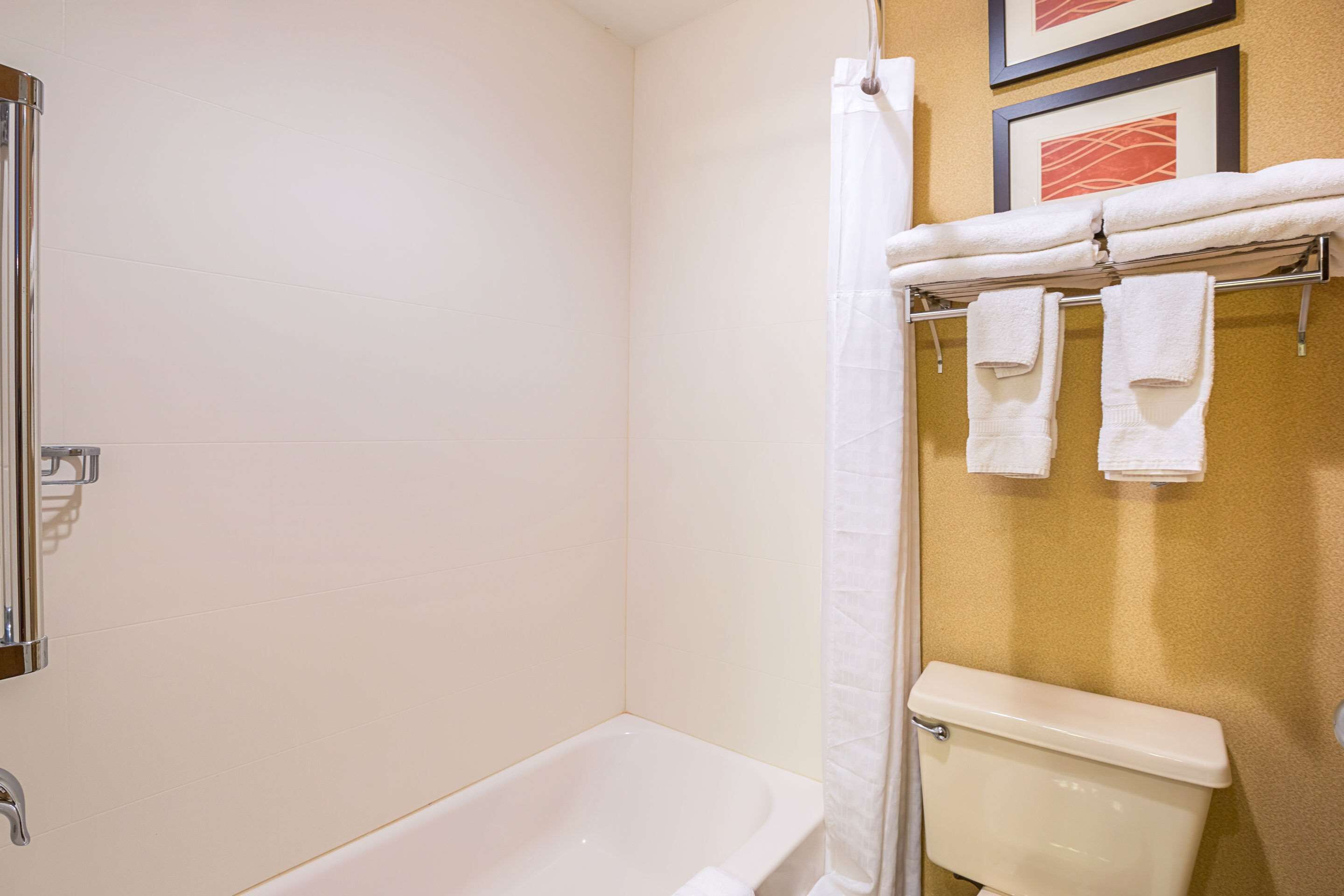 Un baño con bañera, inodoro y toallero con toallas.