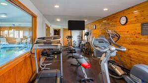 Un gimnasio con cintas de correr, elípticas y una zona de piscina.