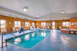 Una piscina interior con sillas de descanso y un jacuzzi.