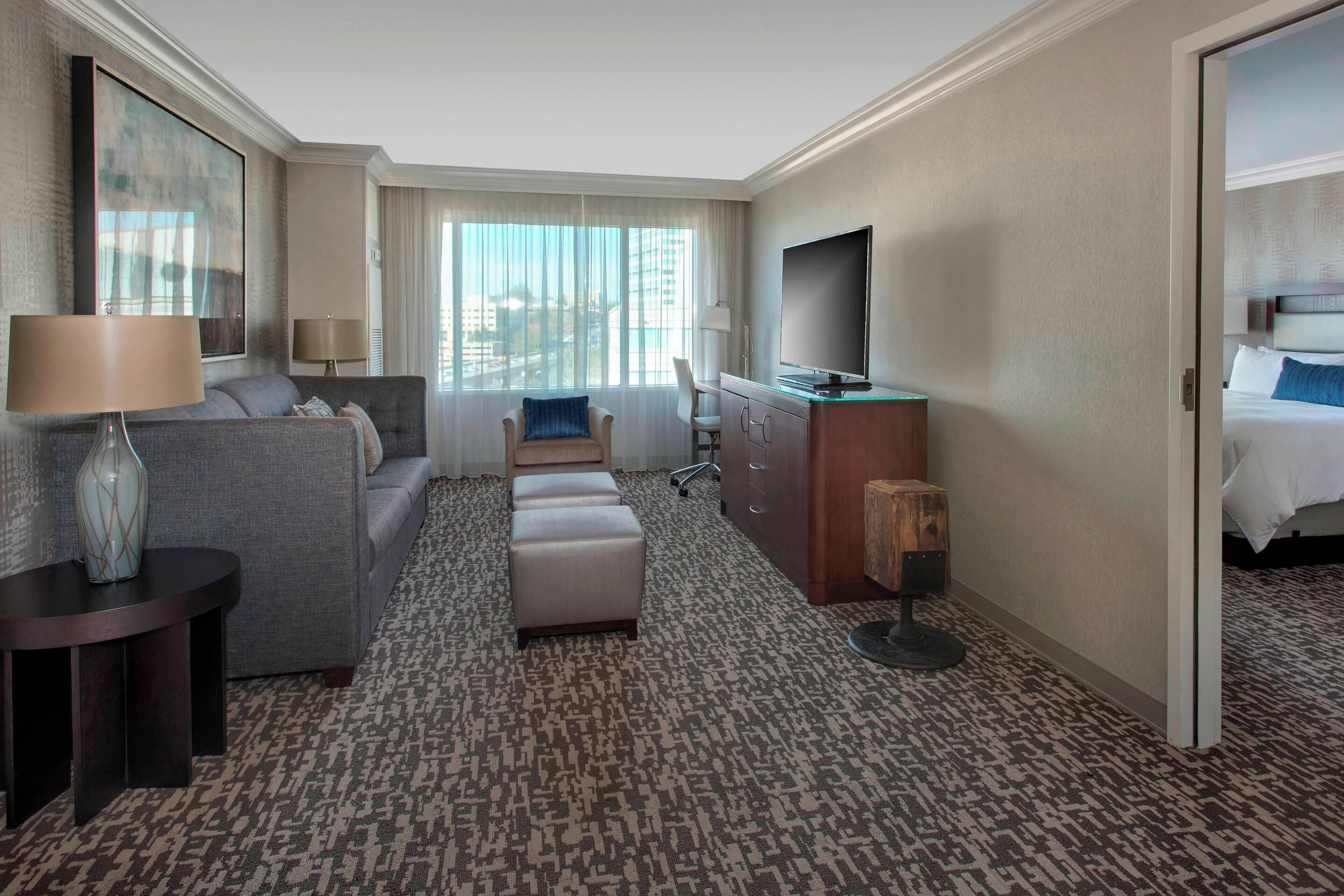 A hotel room with a sofa, a desk, a television, and a bed.