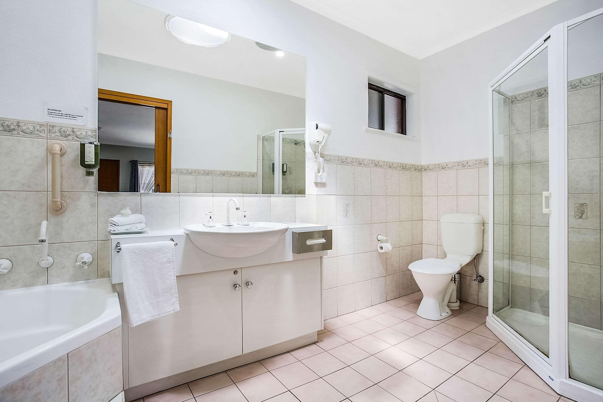 Un baño moderno con bañera, lavamanos, inodoro y cabina de ducha de vidrio.
