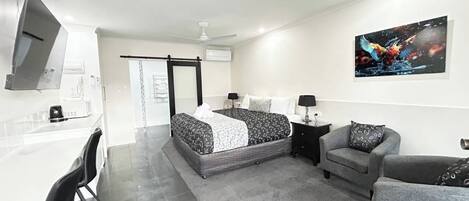 Un dormitorio moderno con cama, escritorio y silla.