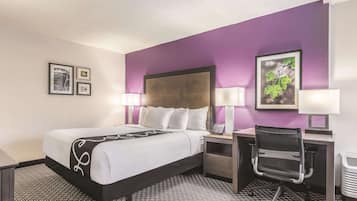 A hotel room with a bed, desk, chair, and two bedside lamps.