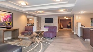 A modern living room with a fireplace, a flat-screen TV, and a reception desk.