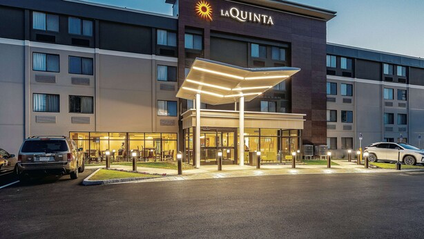 A hotel with a prominent 'La Quinta' sign, a covered entrance, and a parking area with cars.