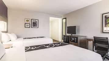 Habitación de hotel con dos camas, un escritorio, un televisor, un microondas y una silla.