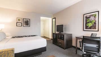 Une chambre d’hôtel comprenant un lit, un bureau avec un ordinateur, une télévision et un petit placard.
