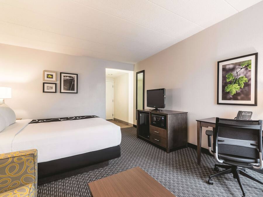 Une chambre d’hôtel comprenant un lit, un bureau avec un ordinateur, une télévision et un petit placard.