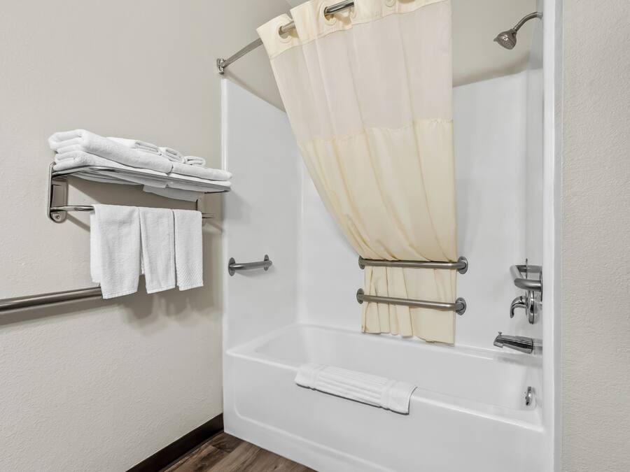 Un baño con bañera, cortina de ducha, toallero con toallas dobladas y cabezal de ducha.
