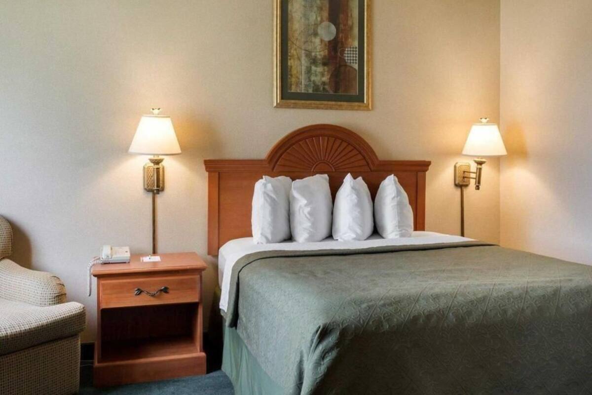 A hotel room with a bed, two bedside tables, a chair, and a painting on the wall.