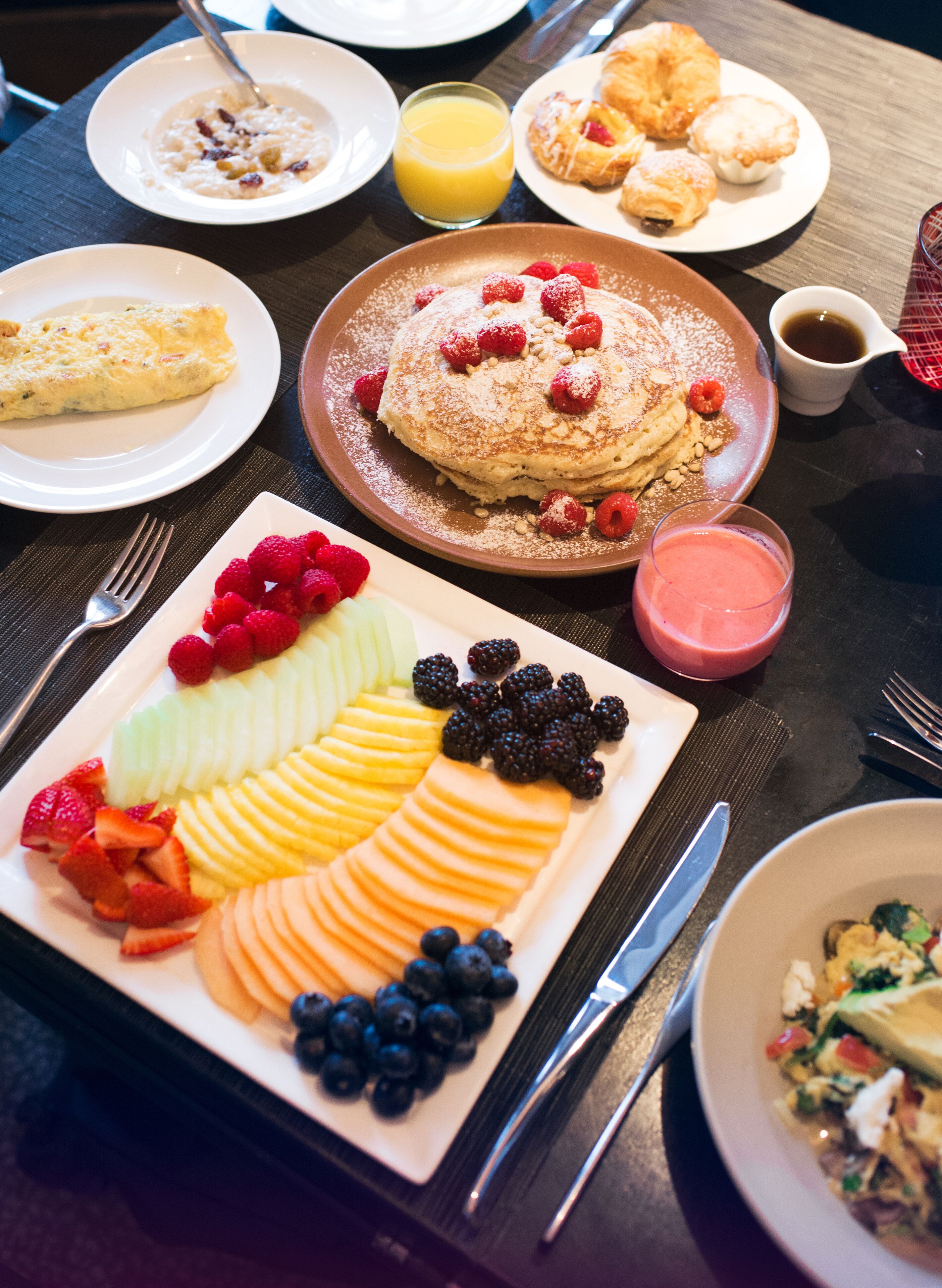 Een ontbijtbuffet met diverse gerechten, waaronder pannenkoeken, fruit en gebak.