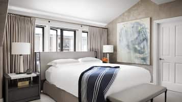 A modern hotel room with a large bed, bedside lamps, a bench, and a painting on the wall.