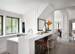 A modern kitchen with a large island, a built-in sink, and a dining area with a high chair.