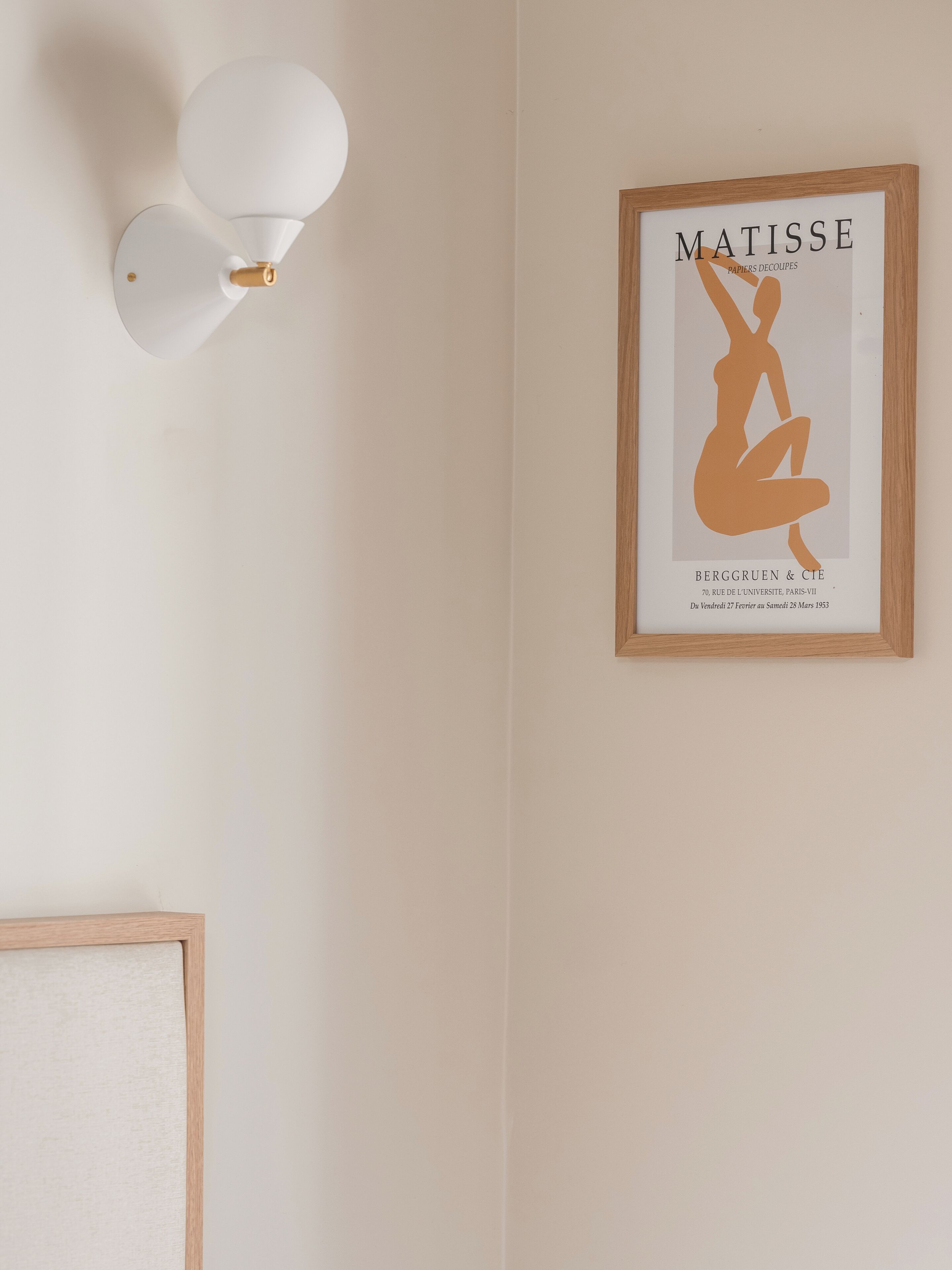 A framed artwork of a nude figure titled 'Matisse' by Berggruen & Cie, with a minimalist wall-mounted light fixture above it.