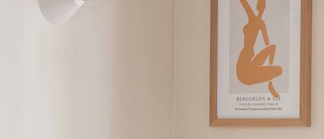 A framed artwork of a nude figure titled 'Matisse' by Berggruen & Cie, with a minimalist wall-mounted light fixture above it.