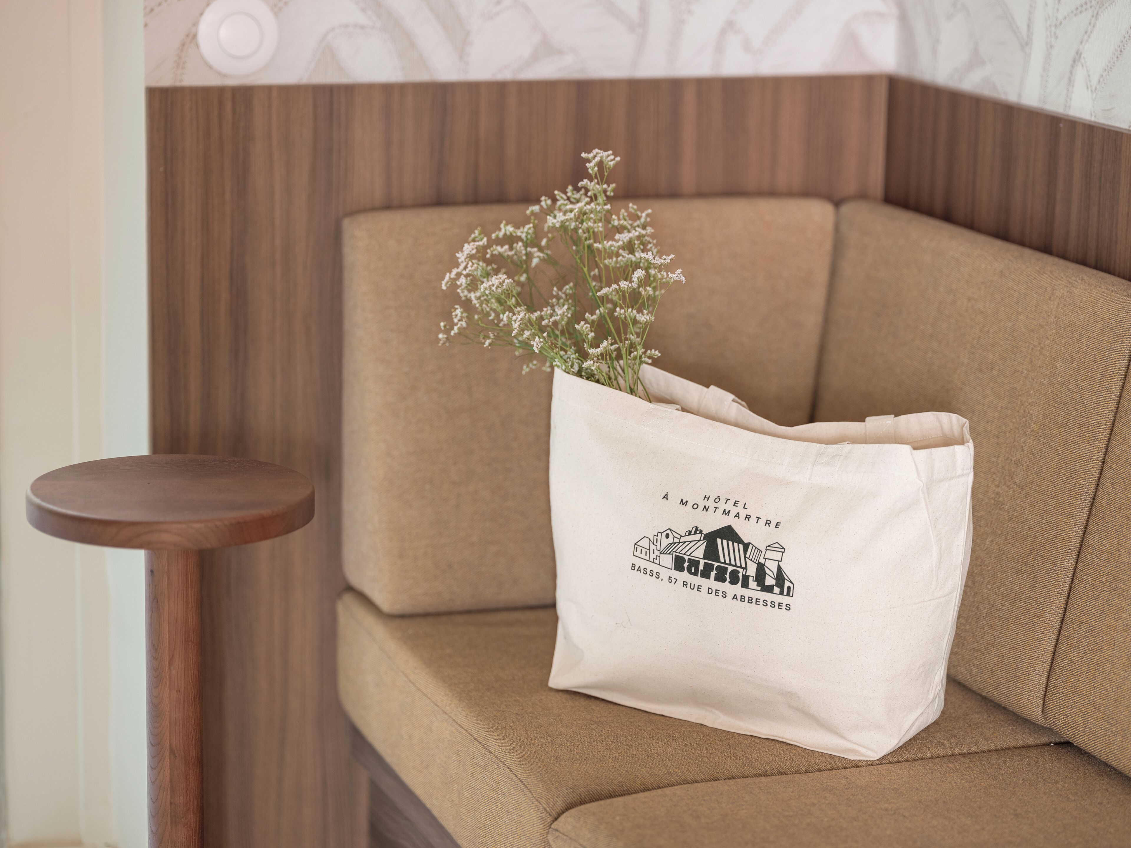 Un sofá beige con un bolso blanco que lleva el logotipo y la dirección de un hotel.