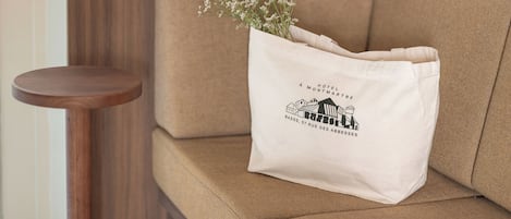 Un sofá beige con un bolso blanco que lleva el logotipo y la dirección de un hotel.