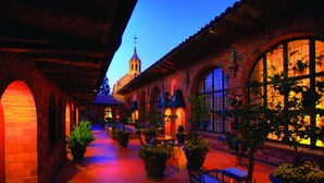 A courtyard with brick buildings, arched doorways, and potted plants. - The Mission Inn Hotel & Spa (Riverside)
