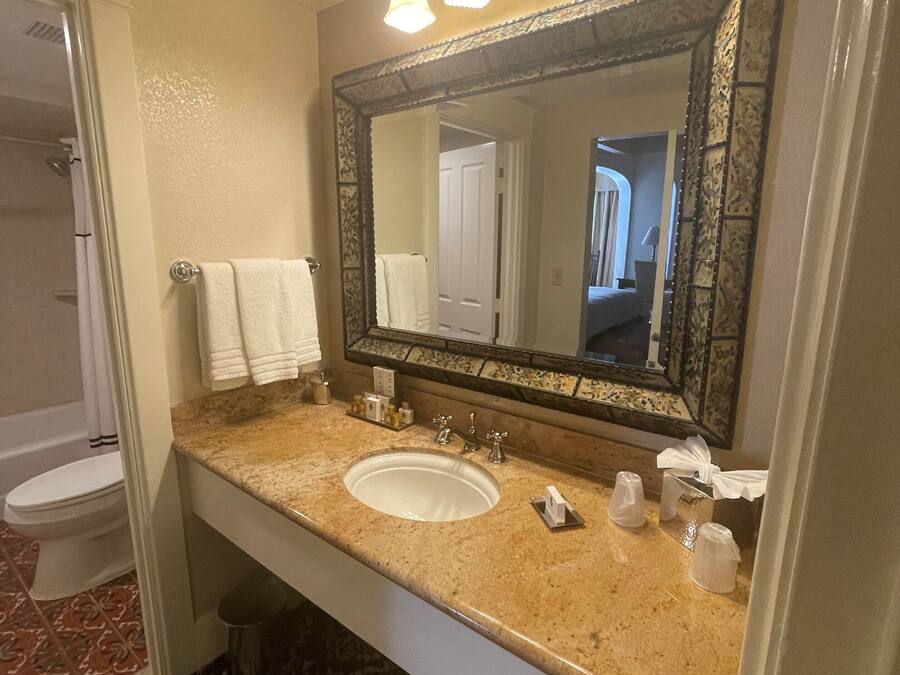 Un baño con lavamanos, espejo y perchero para toallas.