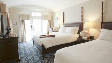 Habitación de hotel con dos camas, un aparador y un ventanal grande con cortinas.