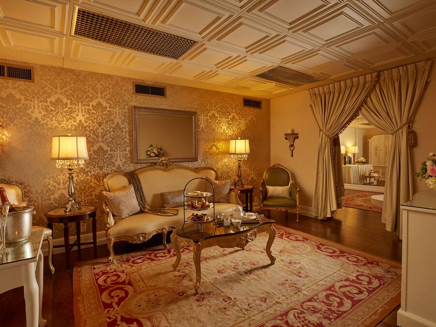 A luxurious room with a sofa, a glass coffee table, and a mirror.