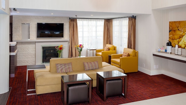 A spacious living area with a large arched window, a flat-screen TV, a sofa, two armchairs, and a coffee table.