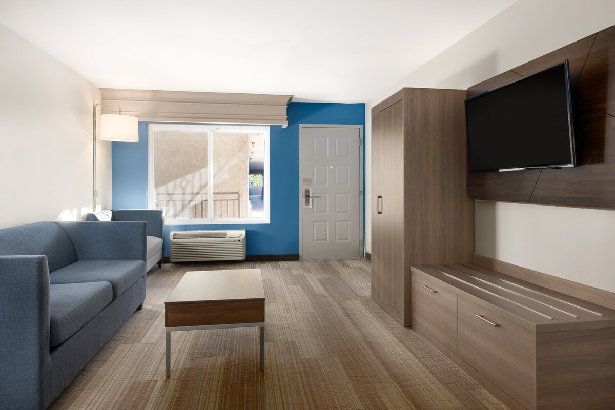 A modern living room with a sofa, a coffee table, a TV mounted on the wall, and a large cabinet.