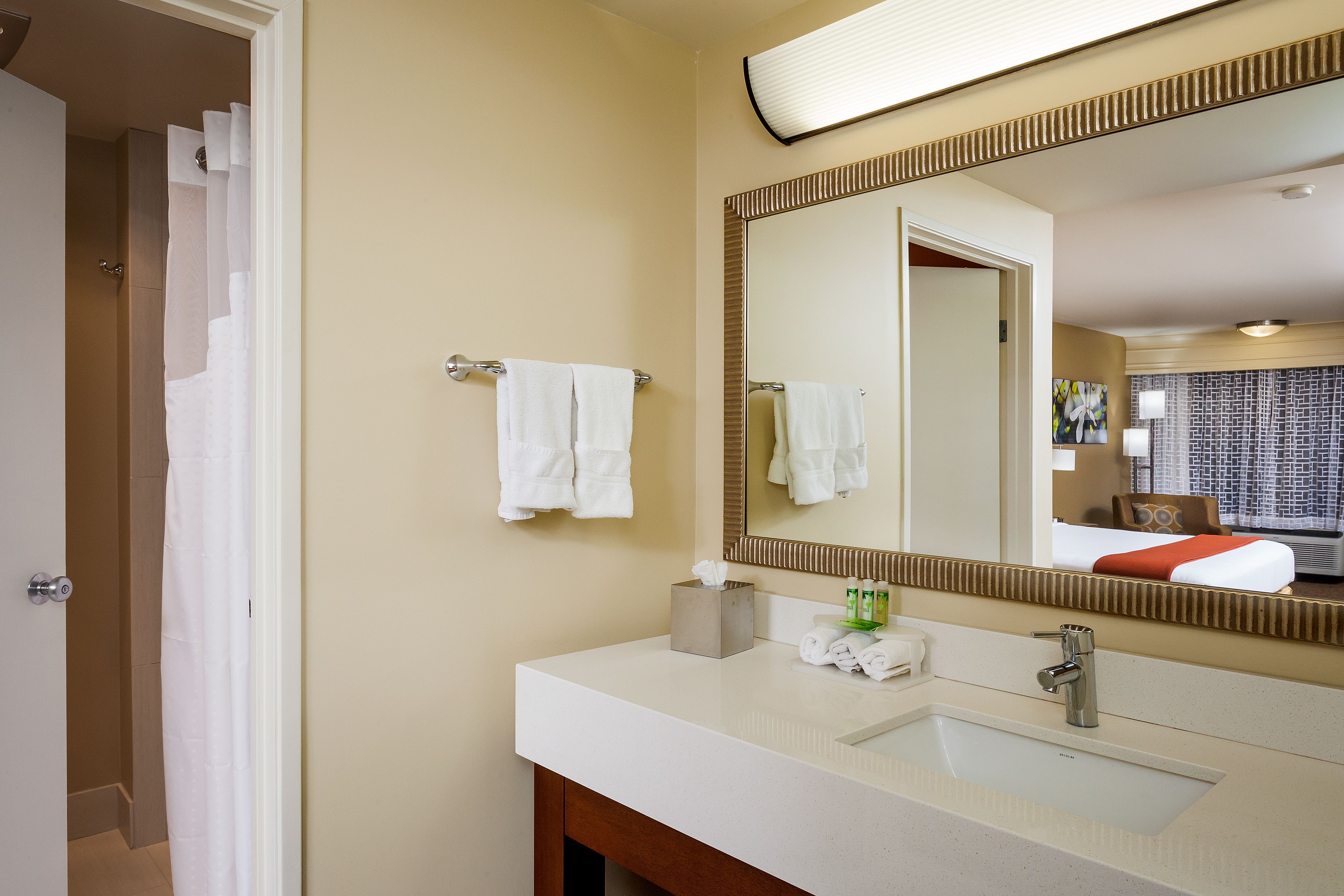 A hotel bathroom with a white sink, a large mirror, and a towel rack.
