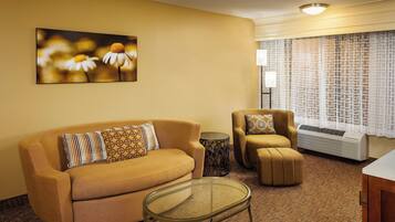 A living room with a sofa, armchair, and glass coffee table.