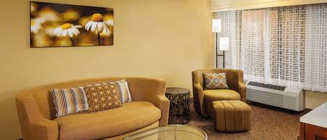 A living room with a sofa, armchair, and glass coffee table.