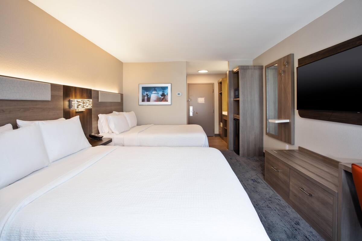 A hotel room with two beds, a TV, a desk, and a wardrobe.