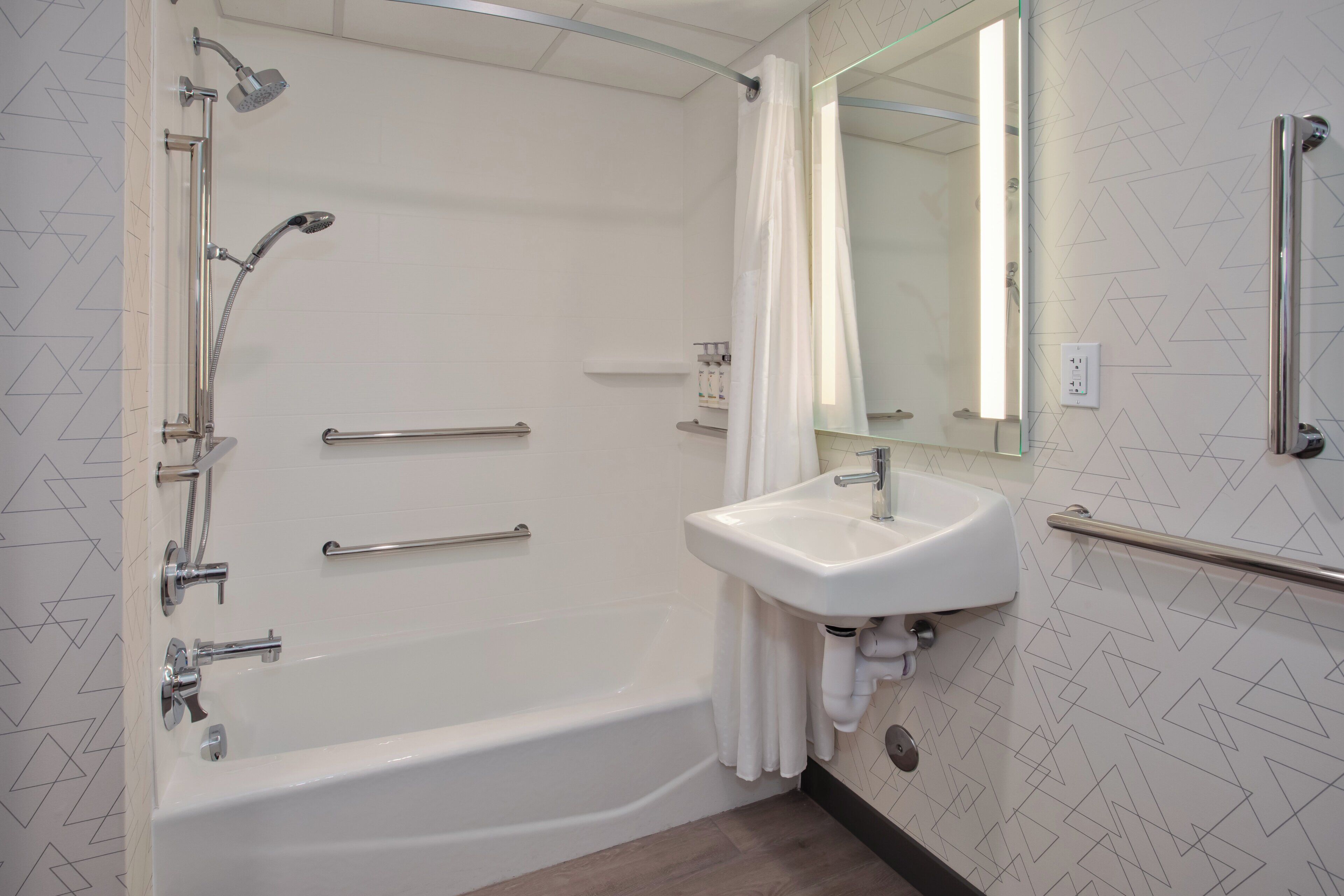 A modern bathroom with a bathtub, a sink, and a shower with grab bars.