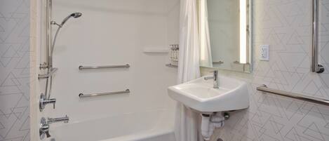 A modern bathroom with a bathtub, a sink, and a shower with grab bars.