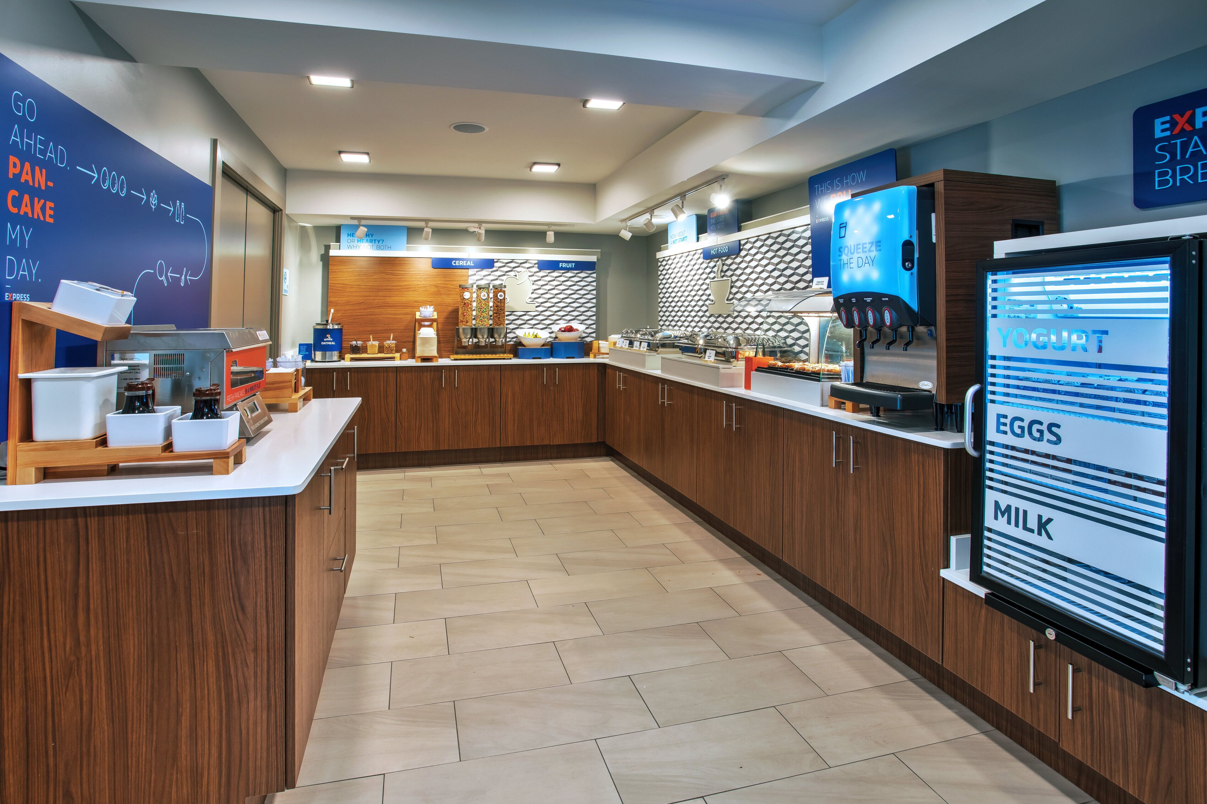 A modern breakfast bar with a digital menu display, wooden cabinetry, and a herringbone-patterned backsplash.