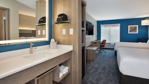 A hotel room with a large mirror, a wooden vanity, a bed, a desk with a chair, and a television. - Holiday Inn Express Kitty Hawk Outer Banks by IHG (Kitty Hawk)