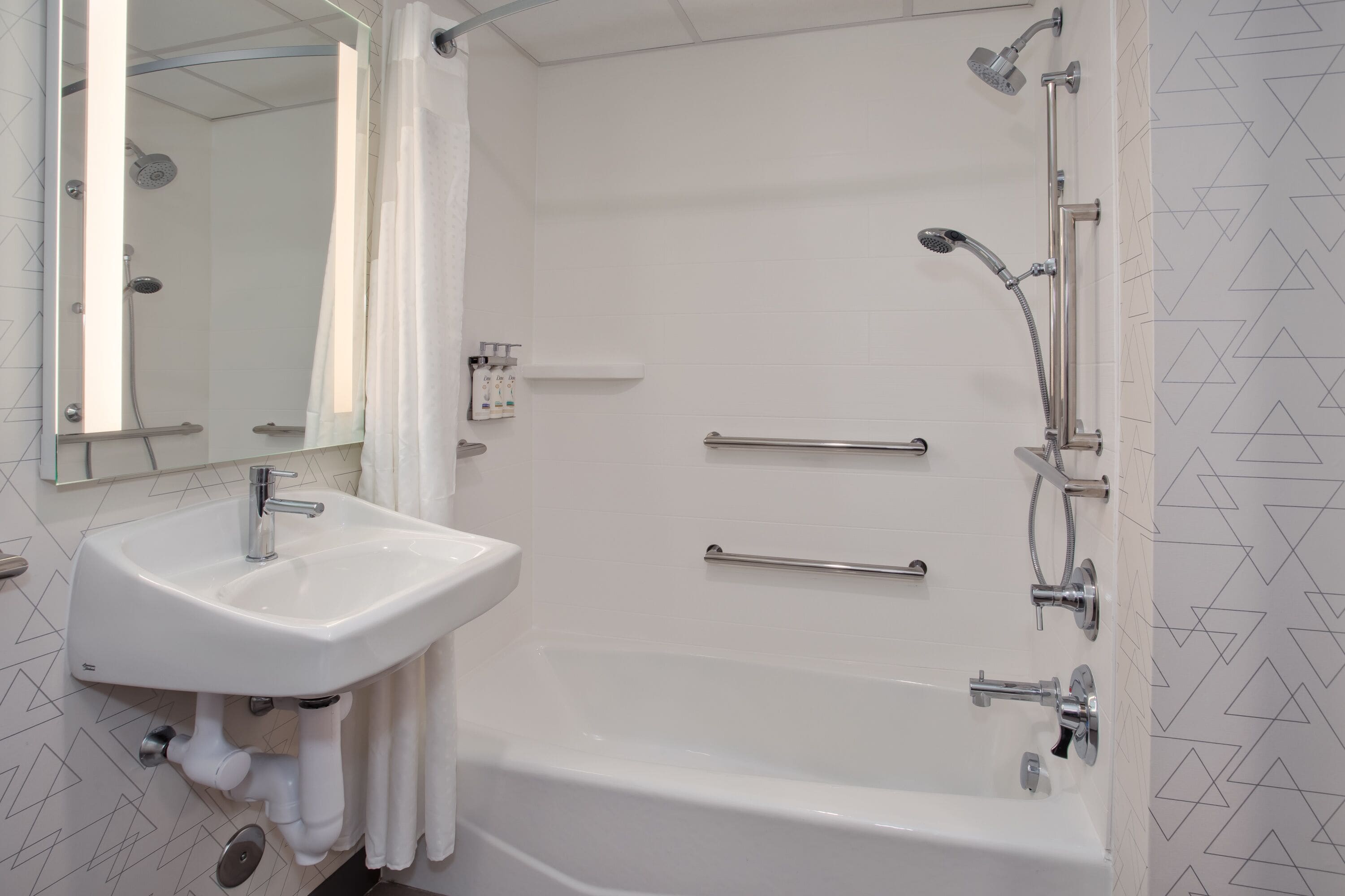 Een badkamer met een witte wastafel, een badkuip en een douche met meerdere kranen.